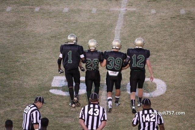 VARSITY FOOTBALL CAPTAINS walk arm in arm to the center of the field before the Homecoming coin toss.