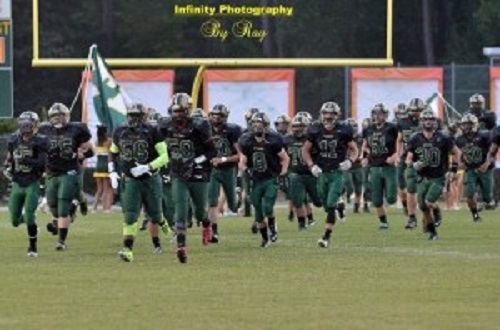 VARSITY FOOTBALL PLAYERS descend on the field before their first home game.