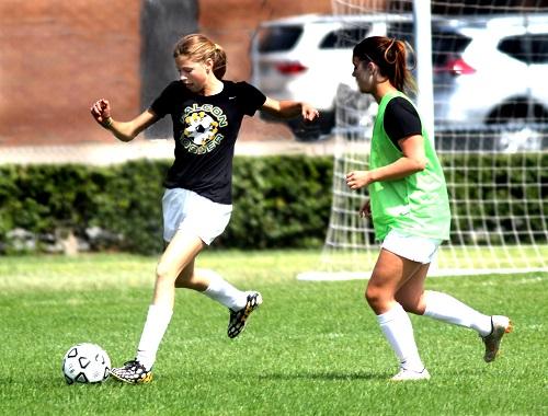 FRESHMAN CAROLINE SULLIVAN keeps the ball away from teammate Skylar Maihles in a pre-game warm up.