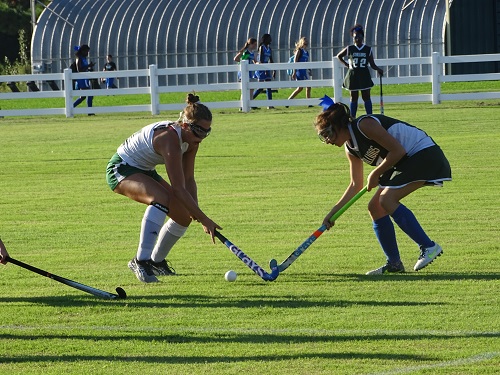 A VARISTY FIELD hockey player fights for the ball.