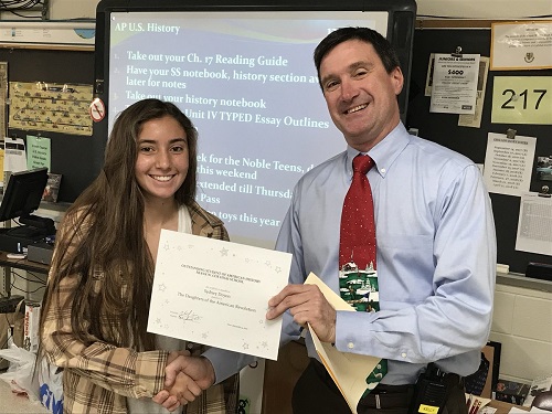 PRINCIPAL DR. MICHAEL Kelly awarded junior Sydney Doyon an Outstanding Student certificate from the National Society of the Daughters of the Revolution yesterday in her AP American History class yesterday.