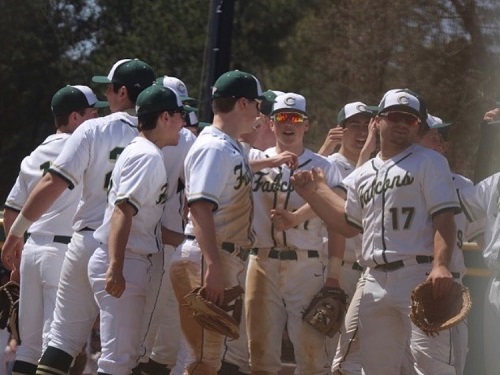 THE BOYS VARSITY baseball team huddle up before they take to the field to play defense.