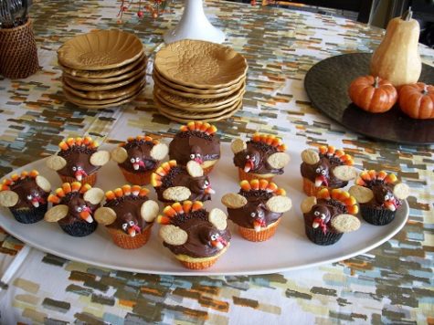 TURKEY DECORATED CUPCAKES sit on a platter, ready to be eaten.  Many kids and families create cupcakes with decorative turkey designs for Thanksgiving.