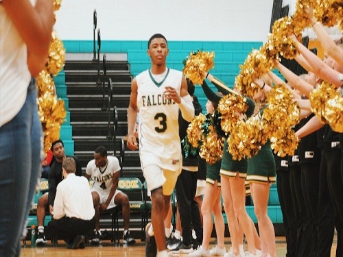 SENIOR KAVON JAMES jogs in through the cheerleaders as one of the starting basketball players. The Falcons went on to beat rival First Colonial.