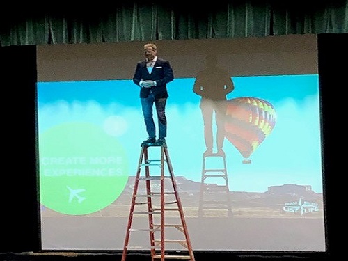 FORMER DENVER BRONCO skydiver Kenyon Salo stands on top of a ladder to encourage students to step out of their comfort zones. Salo was invited by Operation Smile to speak about spreading love and giving back to the community. 