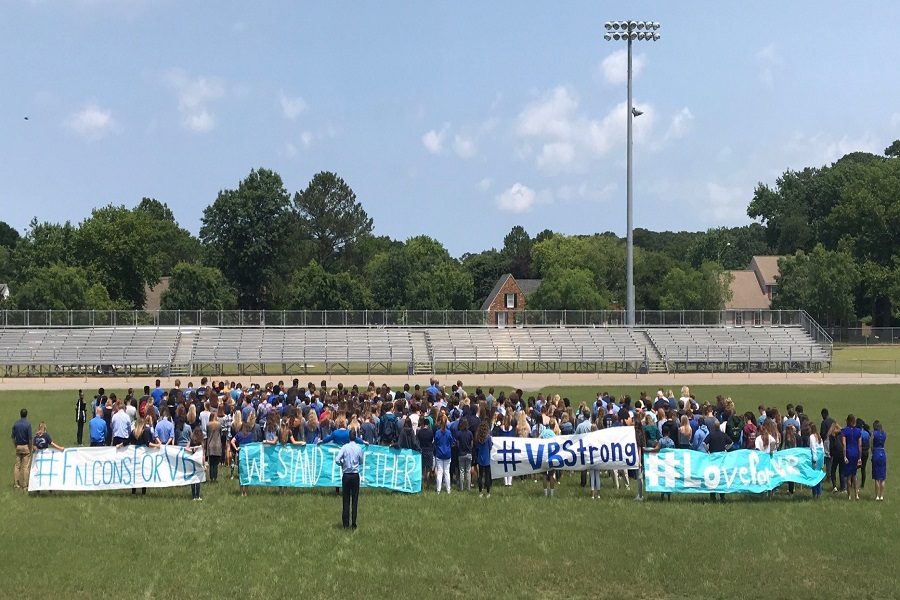 FALCONS STAND TOGETHER on the football field to honor the victims of the recent shooting. The students stood in silence for 12 seconds with posters to share their condolences. 