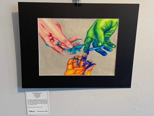 SENIOR MAURA NACEYS piece, The Three Artists, represents the importance of involving oneself in their community. is one piece The piece was created by accident while working with two other friends using chalk and noticed the bright colors left on each of their hands when they finished the assignment.