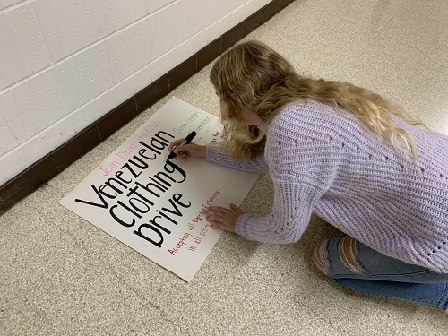 SENIOR AUDRA CHAFFINCH puts finishing touches on a poster for the Venezuelan Clothing Drive. The drive hosted by the Diversity Club will prompt student involvement and community engagement during the holiday season.