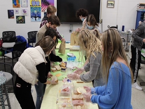 STUDENTS FROM A variety of clubs and activities line up to pack lunches for those who need them during the holidays. Volunteers packed 1,833 lunches total and hope to achieve the same this year.
