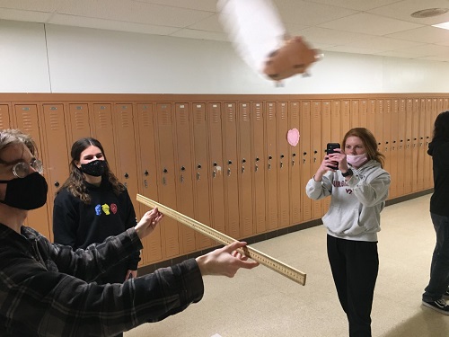 AP PHYSICS STUDENTS junior Cassi Martin and seniors  Evi Capetanakis and Evan Spencer use a meter stick to determine the centripetal force of the flying pig. The pig fly's around to give the students live practice at measuring. 