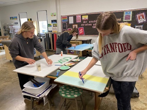 VARSITY FIELD HOCKEY players leave their mark on teacher and coach Mr. Hahns classroom. The team gathered to paint their ceiling tiles after school in the Art room.