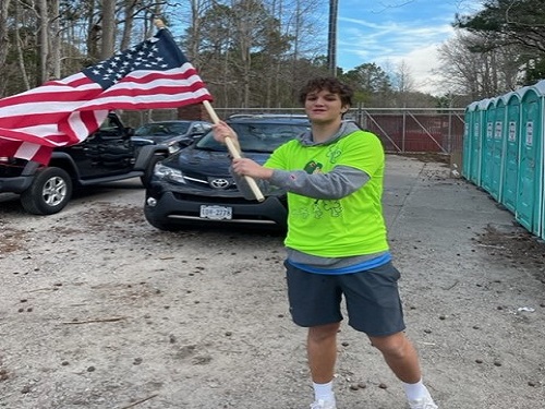 JUNIOR DYLAN KASSIR waves the American flag in solidarity for attendees who couldnt make the race due to pandemic issues.  Kassir volunteered his time to the Class of 2023 at the 50th Shamrock Marathon at the Oceanfront.