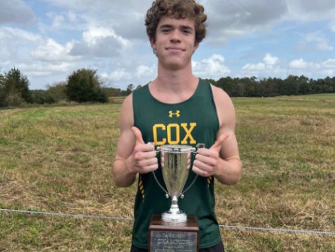 SENIOR LARRY ELFELT takes pride in holding the 2022 region championship trophy for boys cross country. His many years of training prepared him to be a titleholder his senior year. 