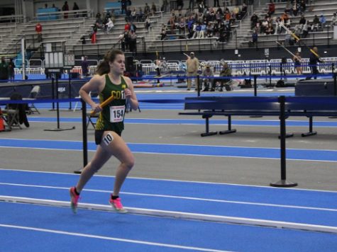 SENIOR ANNIE BUSCH races to the finish line while her teammates cheer her on. Busch knew she had the teams support while trying to qualify for states.
