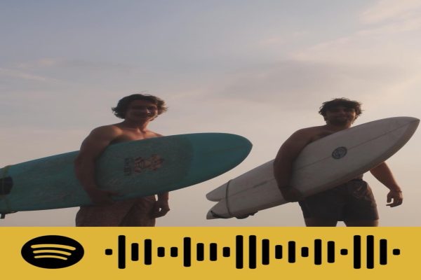 TWO FRIENDS CATCH waves at sunset in Nags Head, North Carolina. Listening to Mays Spotify playlist tunes fit in well while surfing as the sunlight dims.