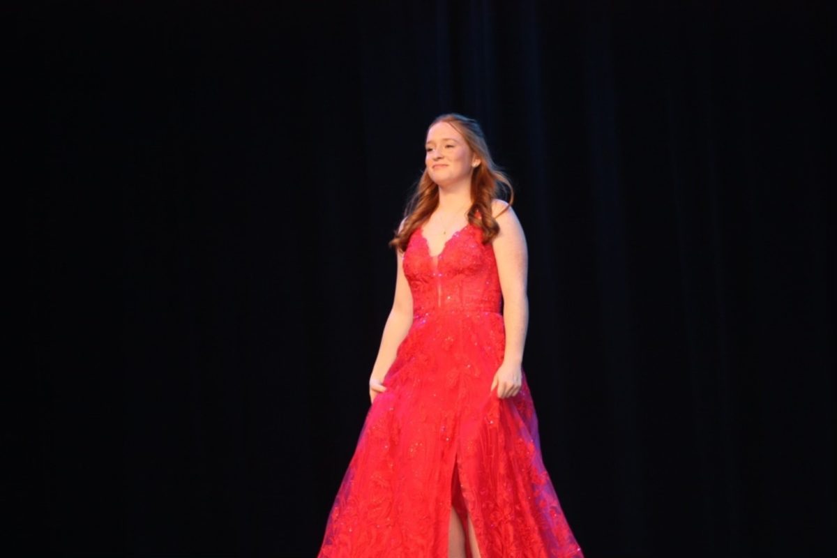 SENIOR ELLIE BUFFKIN struts in her beautiful red prom dress on the CHS stage. Prom dress shopping isnt always easy; however, many of the different styles are often admired for their elegance and variety. 