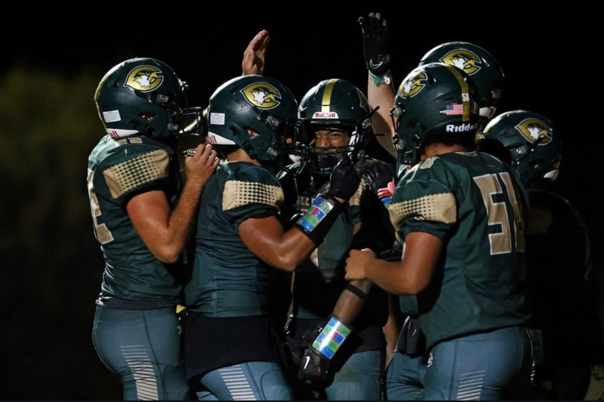 FALCONS GATHER AROUND junior Jiwan Mack to celebrate his touchdown during the second half of the game. The boys came back for the win in the end, now boasting a 2-0 record.