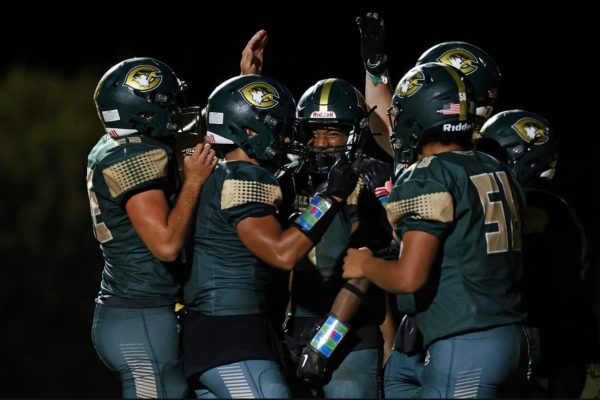 FALCONS GATHER AROUND junior Jiwan Mack to celebrate his touchdown during the second half of the game. The boys came back for the win in the end, now boasting a 2-0 record.