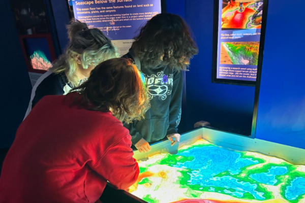 CHS ART STUDENTS examine a topography map in the aquarium. As they observe, they will be jotting down future reference points.