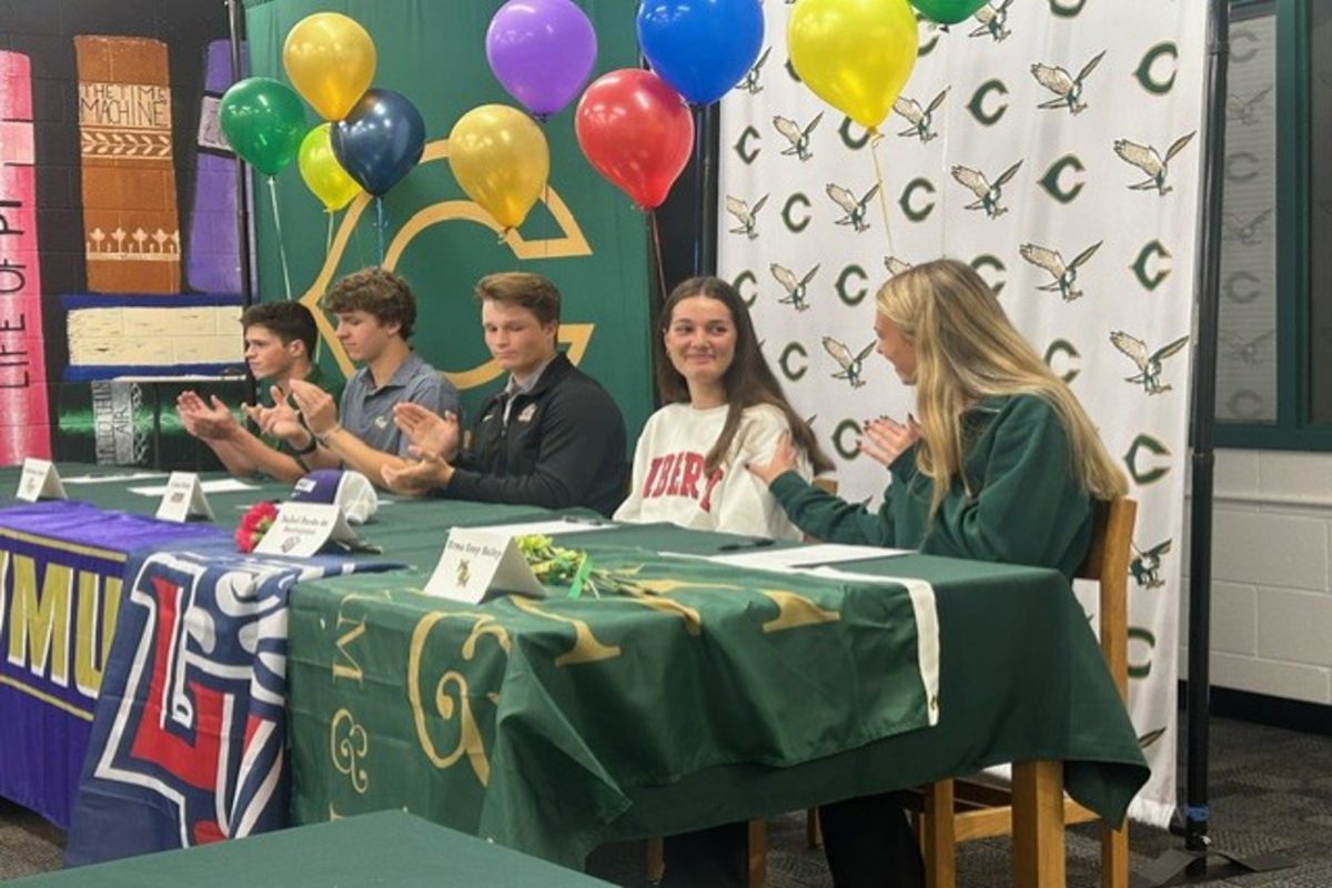 FALCON SENIOR ATHLETES congratulate each other on their college commitments. The students were applauded by their friends in the audience. 