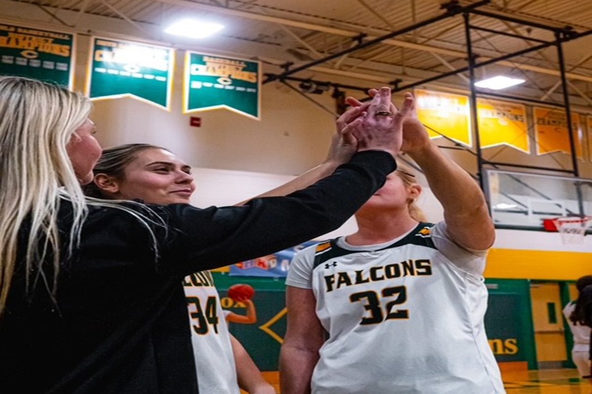 LADY FALCON BASKETBALL players senior Erma Bailey (middle) and sophomore Campbell Wight (right) high-five Coach Mat (left) before their game last week. The girls are now 6-10 with five games left to go.