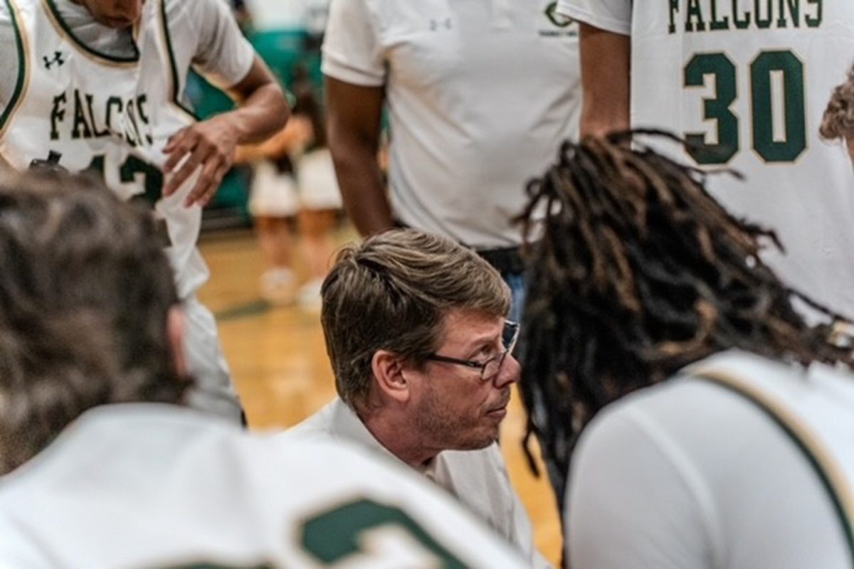 SENIOR ROY COLES dribbling past LONGTIME BOYS VARSITY basketball coach Bobby Wolfe calls plays during a time out. Wolfe's wisdom and experience was helpful to his players, as the Falcons took down Bayside High School at home. 