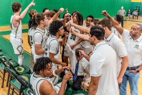 VARSITY BOYS BASKETBALL players huddle up during a team talk with Head Coach Bobby Wolfe. The team stayed strong through an eventful, yet tough season, ending with a 10-12 record overall.